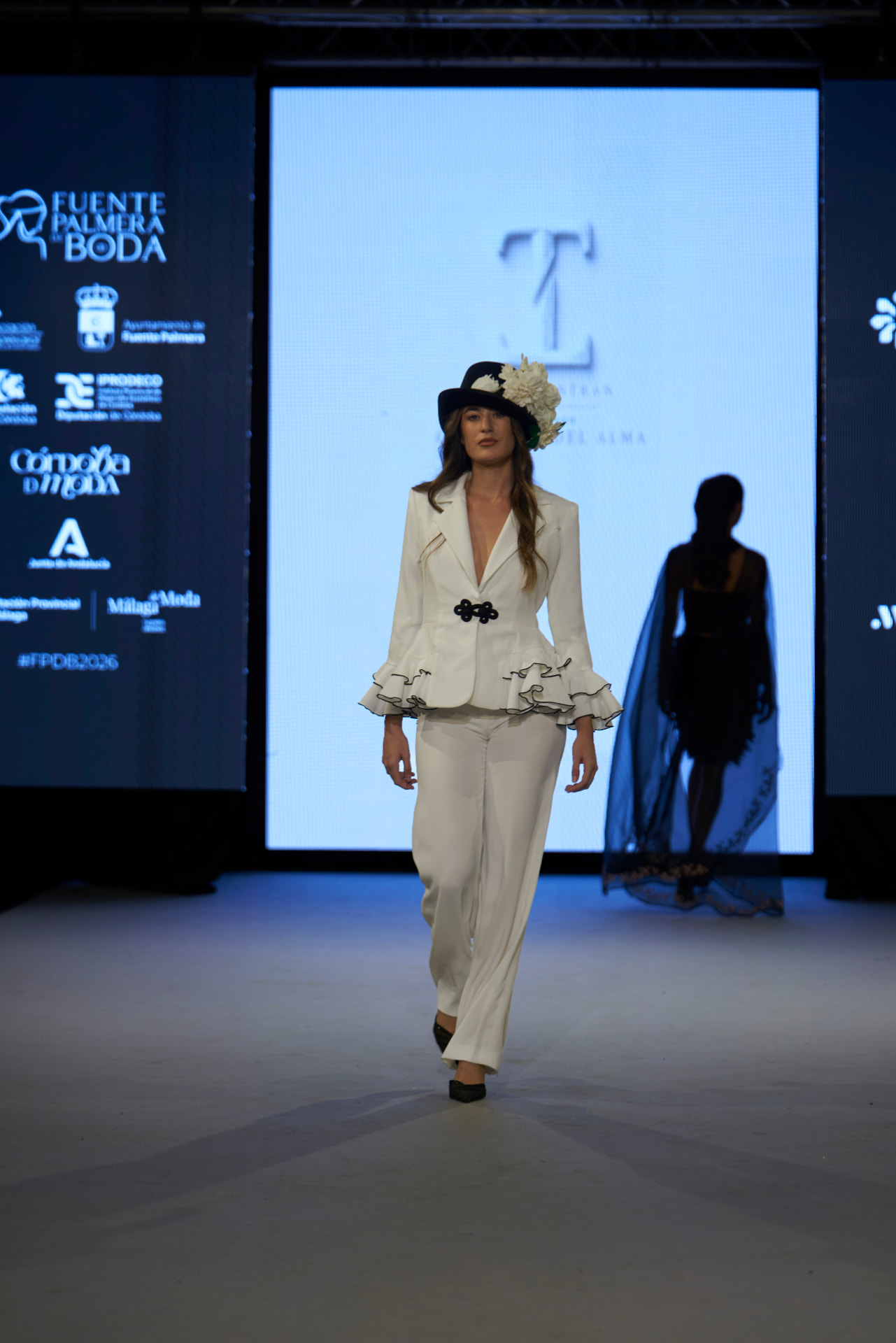 Chaqueta blanca con volantes ribeteados en negro y sombrero con flores