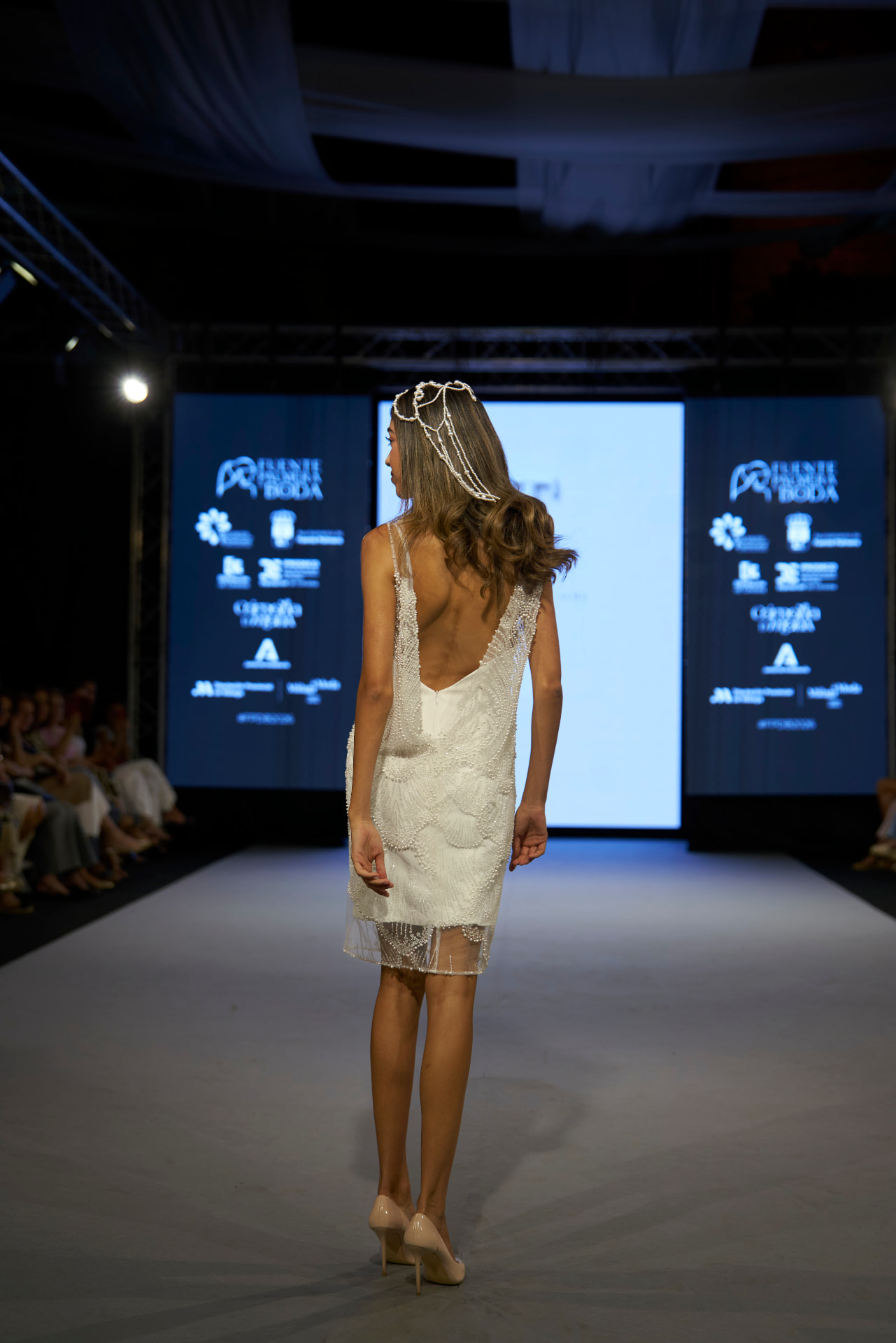 Vestido corto con escote abierto en la espalda y tocado de perlas, de espaldas