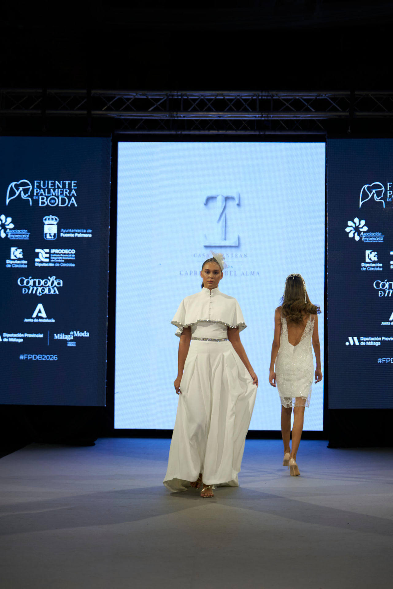 Vestido de novia largo con capa corta ribeteada de pedrería y tocado con redecilla