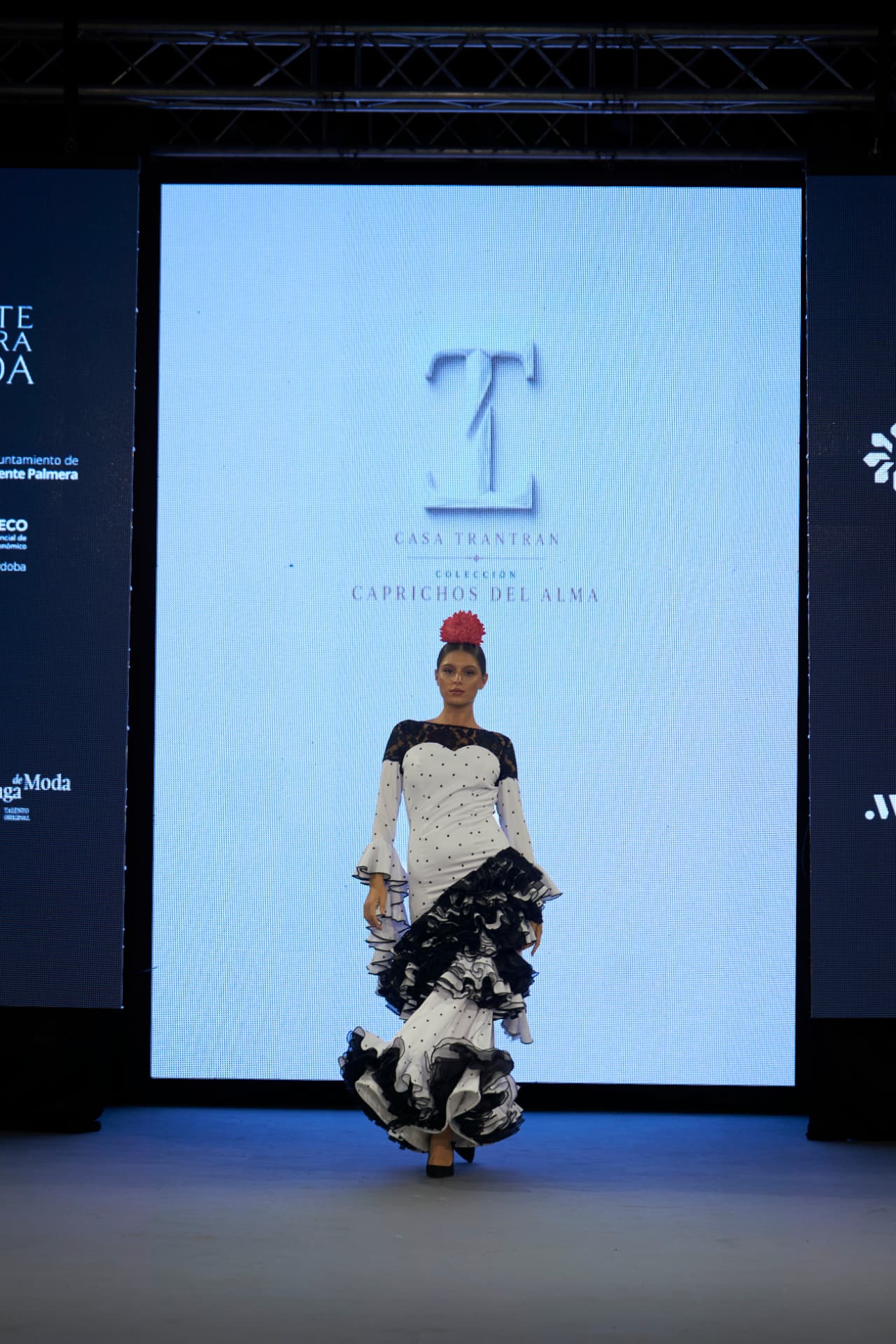 Traje de flamenca blanco de lunares con canesú de encaje negro y volantes, caminando
