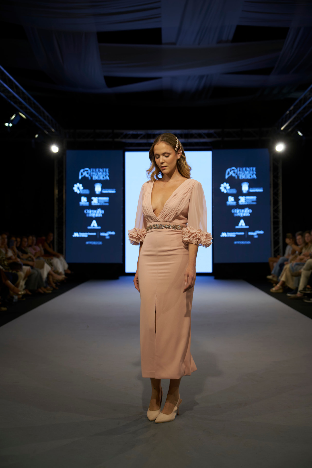 Vestido rosa de escote en pico con cinturón joya y puños de volantes, de frente