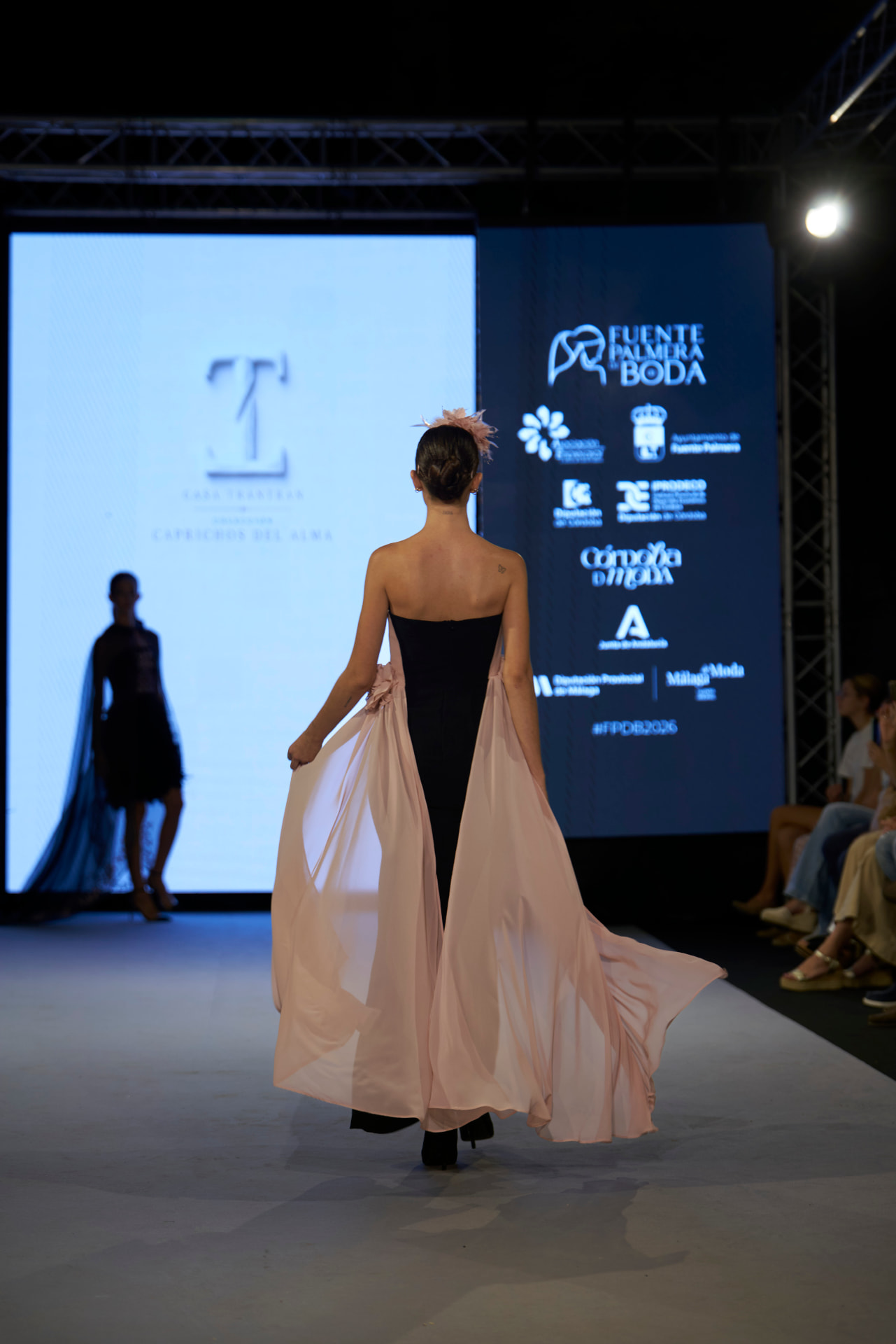 Vestido negro con amplia cola de gasa rosa y espalda descubierta, de espaldas