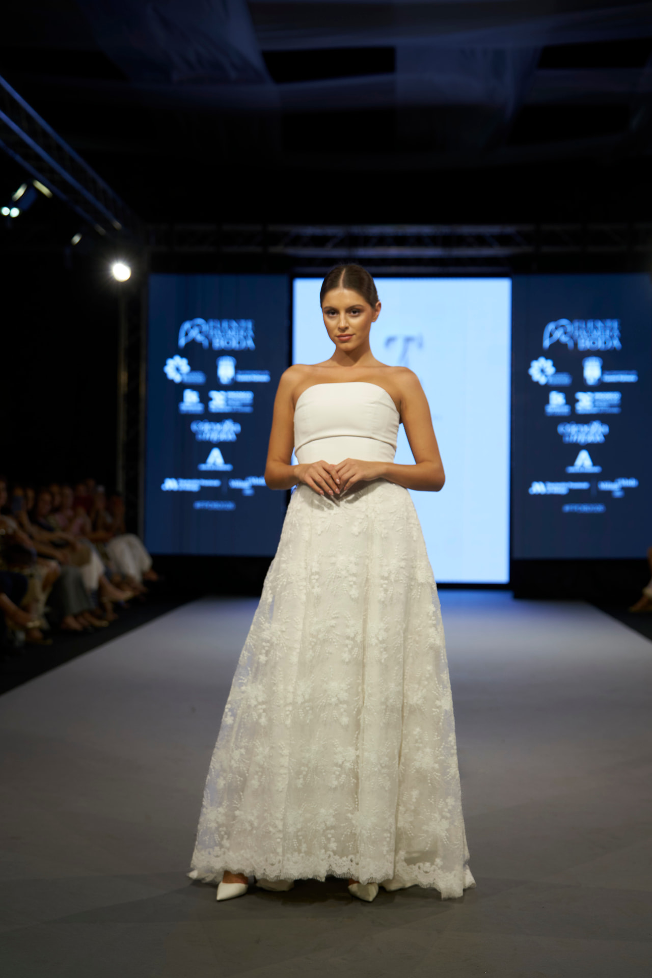 Vestido de novia palabra de honor de encaje floral avanzando por la pasarela, de frente
