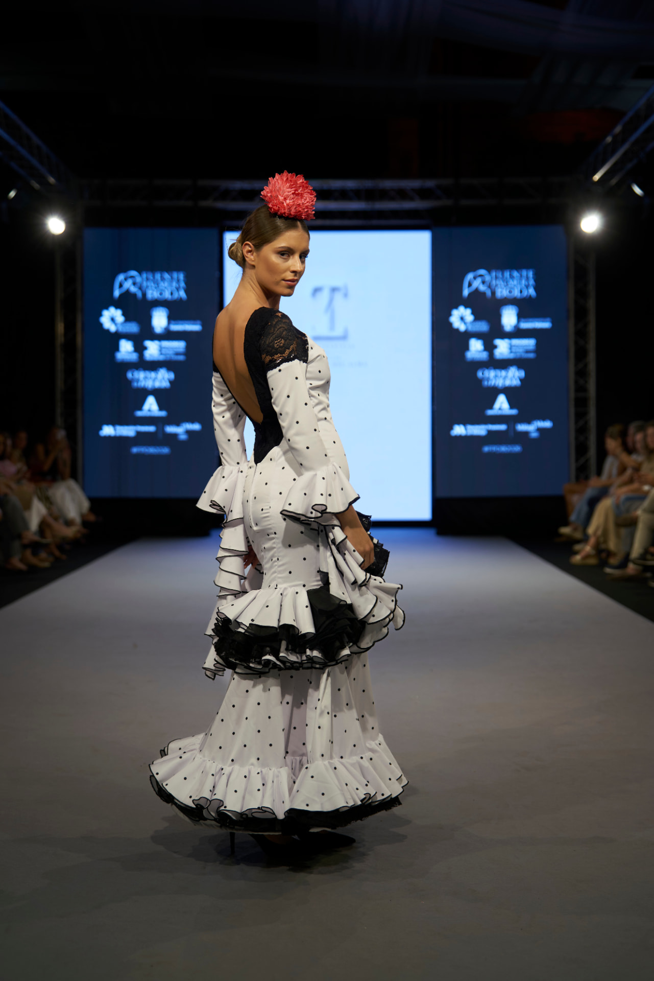 Traje de flamenca blanco de lunares con espalda descubierta de encaje negro, mirando atrás